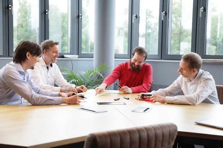 Projektteam bei einer Besprechung an einem Tisch sitzend.