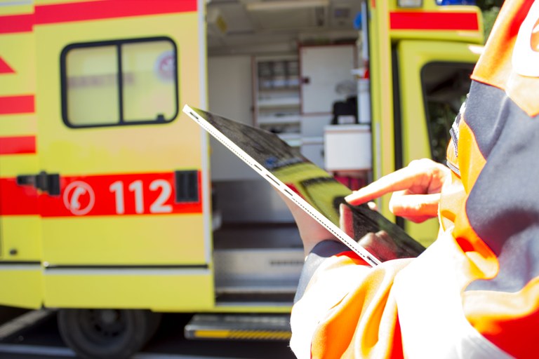 Sanitäter mit Laptop vor Krankenwagen